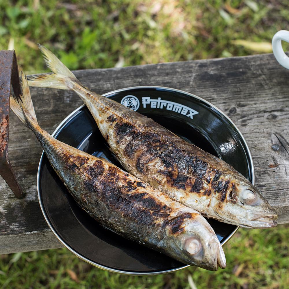 Two grilled whole fish served on black enamel Petromax plates resting on a rustic wooden surface, ideal for Farm, Garden & Tool, Kitchen & Food, Camping, Dinnerware, Best Sellers, and Promo Eligible collections.