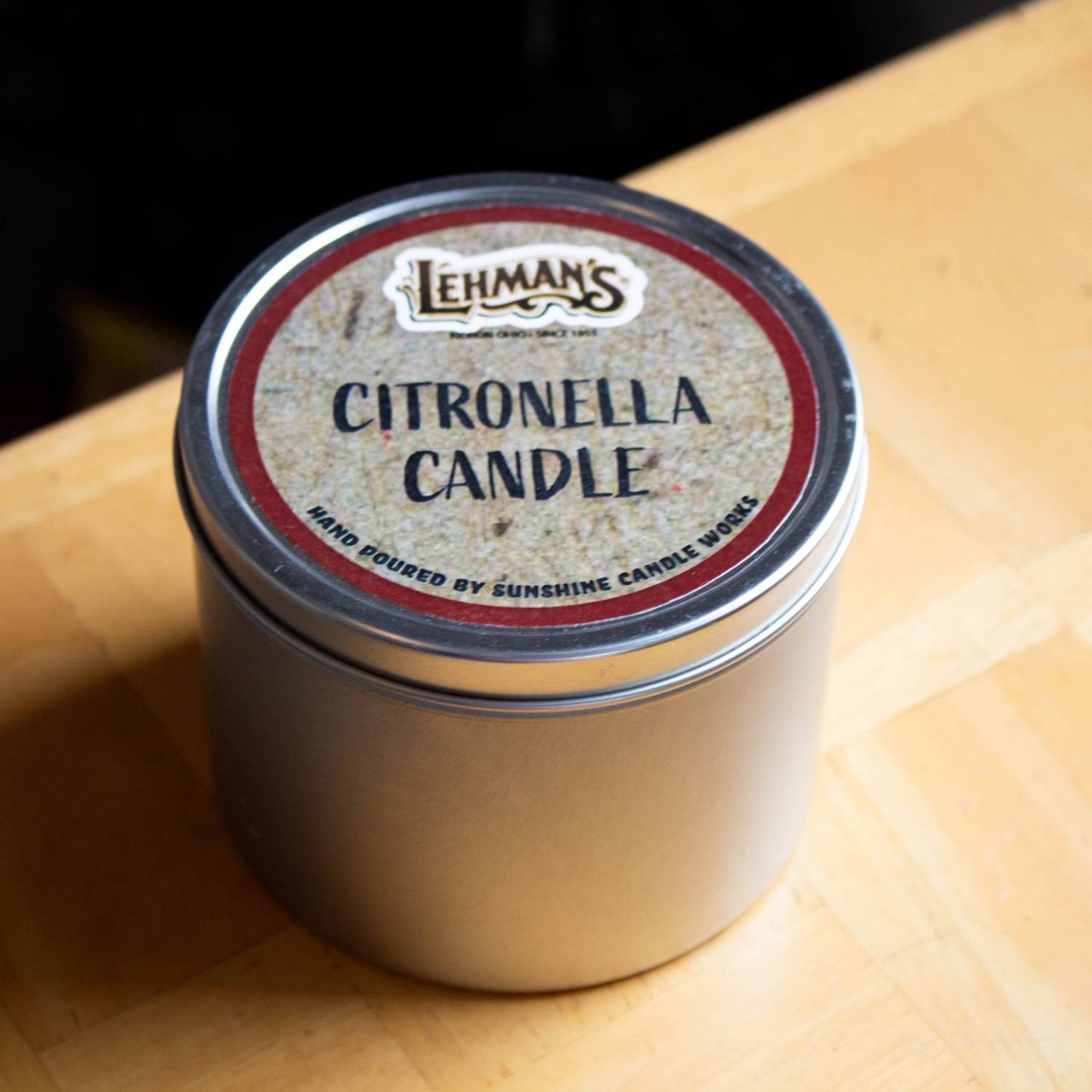 Compact hand-poured citronella candle in a silver tin with a rustic label, handcrafted and ideal for outdoor use in camping, pest control, and garden lighting collections.