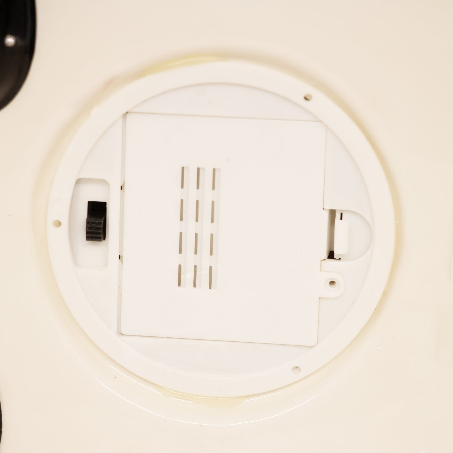 Close-up of a white battery compartment with a sliding lock and ventilation slits, handcrafted for use in Home & Decor, Holiday Decor, Best Sellers, and Promo Eligible collections.