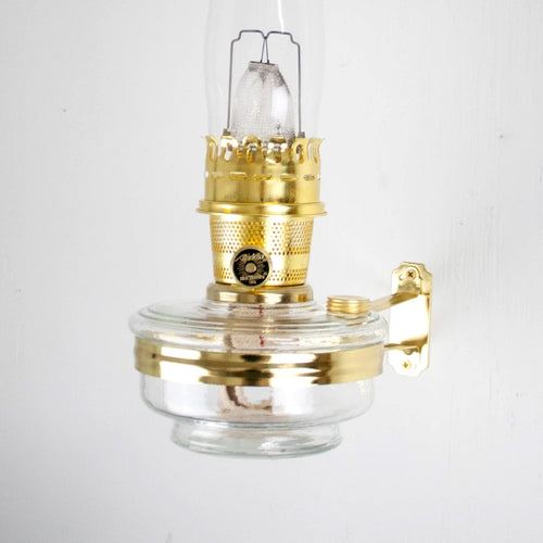 Handcrafted clear glass oil lamp with polished brass burner and wall bracket, designed for mounting classic Aladdin-style lamps, featured in Lamps & Lighting, Oil Lamps, Wall Lamps, Best Sellers, and Promo Eligible collections.