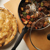 Covered stainless steel saucepot with cooked beef stew including carrots, celery, and potatoes, alongside a golden-brown homemade pie, featured in Kitchen & Food, Cookware, and Best Sellers collections.