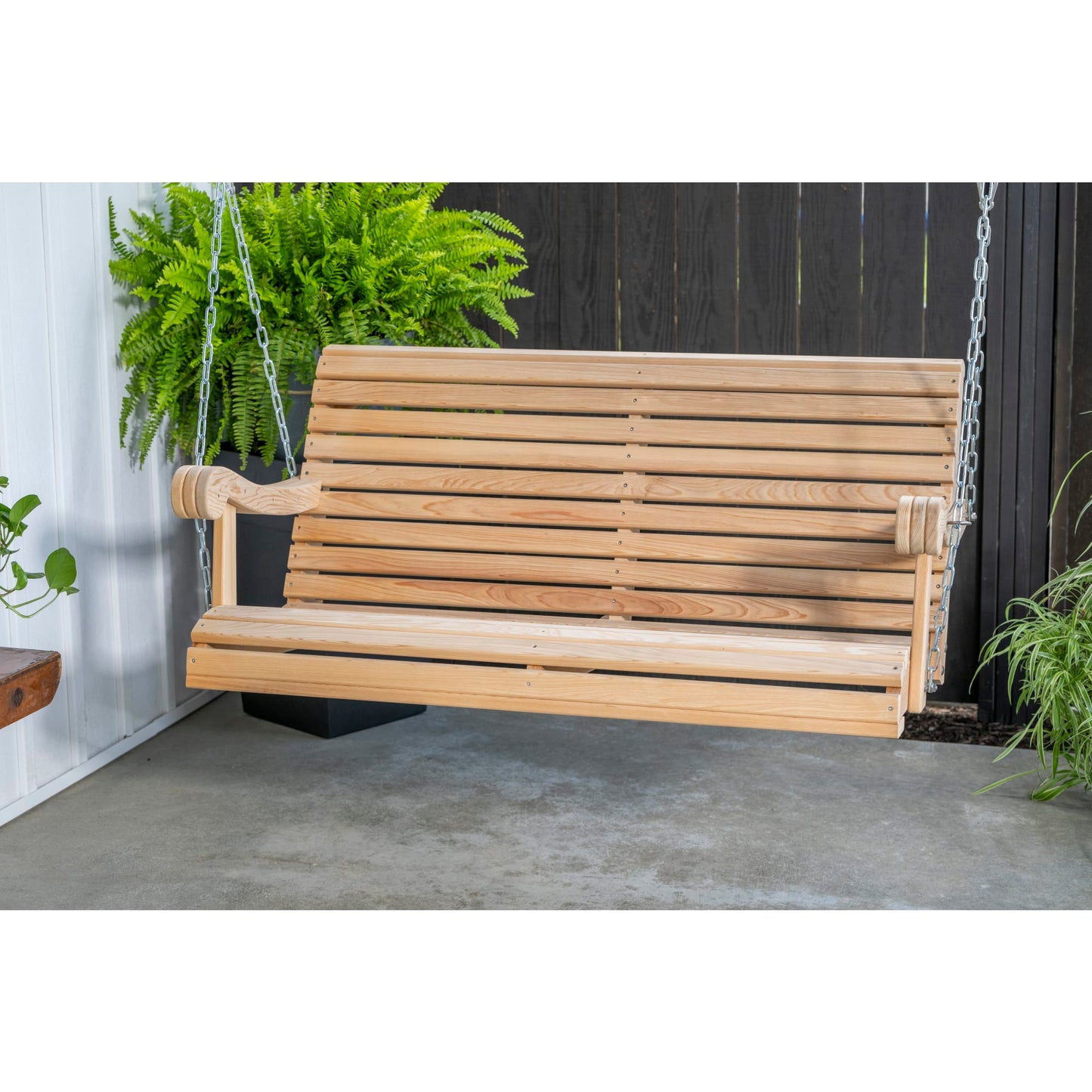 Handcrafted 4 ft cypress porch swing suspended by sturdy chains, showcasing smooth wood grain and classic design, surrounded by green plants in a cozy outdoor setting.