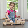 Young girl playing indoors with a handcrafted wooden truck and stock trailer made in USA, Amish made, ideal for children's toys, indoor play, and wooden toys collections.