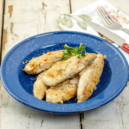 Cooked chicken tenders seasoned and arranged on a speckled blue enamel plate, garnished with fresh parsley, set on rustic wooden surface with cutlery in the background.