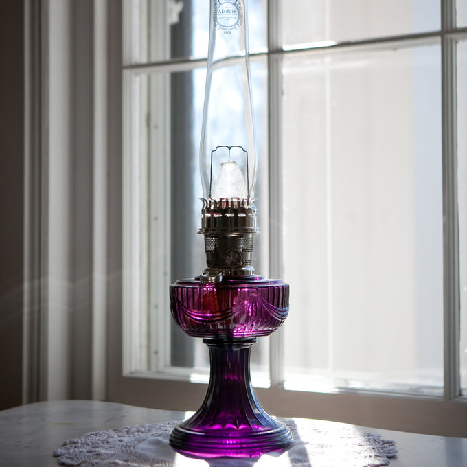 Handcrafted oil lamp featuring a purple Lincoln Drape glass base, clear tall chimney with embossed logo, and brass burner, perfect for Farm, Garden & Tool, Lamps & Lighting, Oil Lamps, Table Lamps, Best Sellers, Homesteading, and Promo Eligible collections.