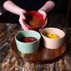 Three ceramic condiment bowls in red, green, and beige with subtle woven texture, filled with sauces and arranged on a handcrafted wooden Lazy Susan turntable in Kitchen & Food collections.