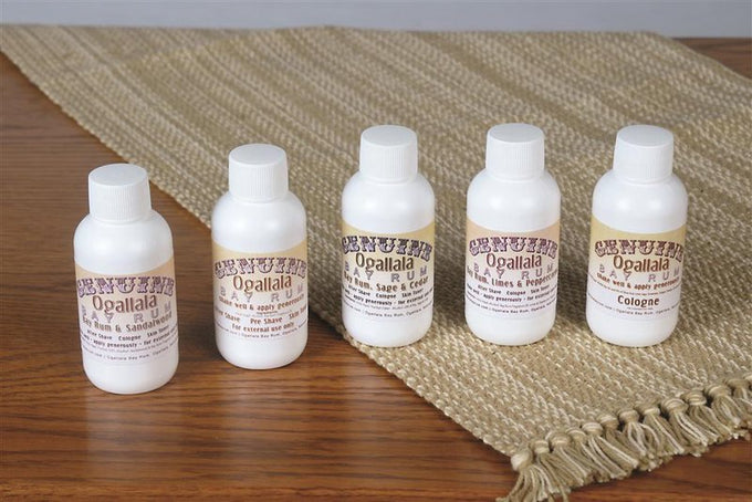 Set of five handcrafted Ogallala Bay Rum grooming bottles featuring aftershave and four cologne scents, displayed on a woven natural fiber runner, USA Made collection.