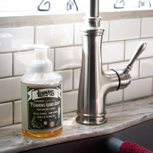 Clear pump bottle of Lehman's handcrafted moisturizing foaming hand soap with peppermint scent, made in USA using natural oils like olive, coconut, sunflower, honey, and jojoba, ideal for Health & Wellness, Grooming, and Soaps collections displayed beside a kitchen sink faucet.