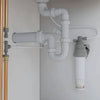 Under-sink water filtration system with white PVC pipes and fittings connected to a compact ceramic filter cartridge, designed for easy installation in home appliances and water treatment setups.