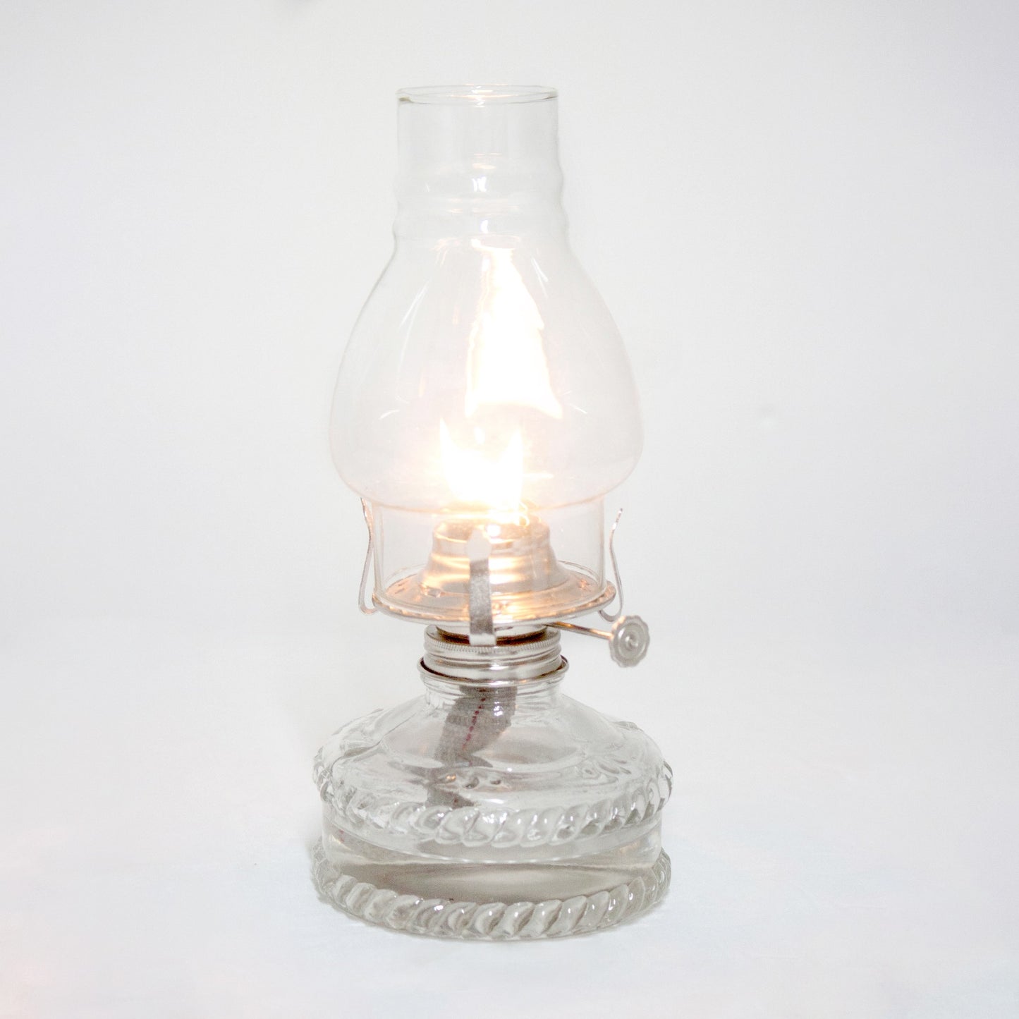 Handcrafted clear glass oil lamp with a decorative braided base and bright flame under a chimney, ideal for farm, garden, emergency use, and part of best-selling lamps collection.