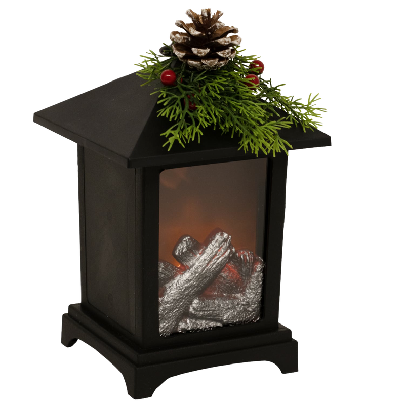 Black metal lantern featuring a cozy LED faux fireplace with silver logs, topped with festive pine sprigs, red berries, and a pinecone, perfect for Home & Decor, Holiday Decor, Best Sellers, and Promo Eligible collections.