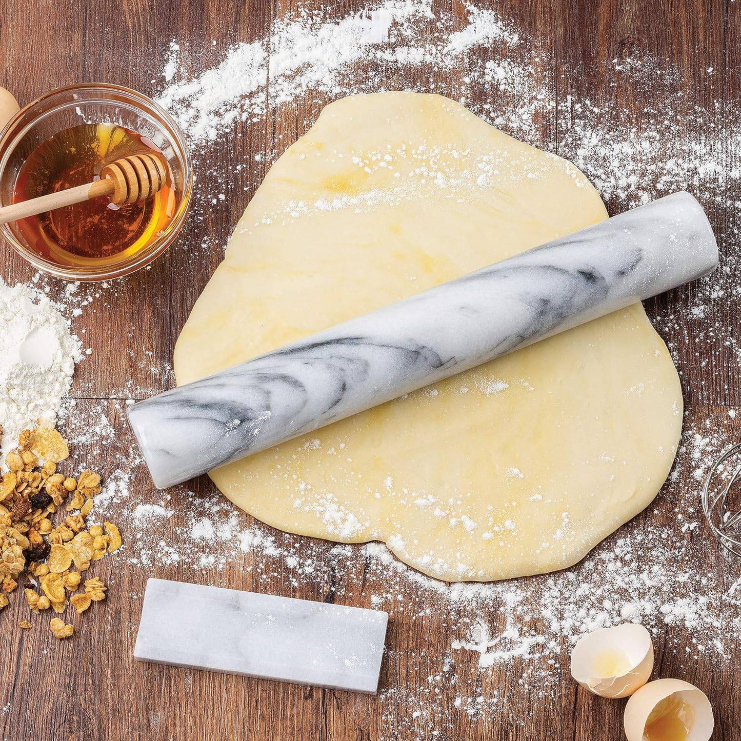 Handle-free marble rolling pin on wooden surface with rolled dough, cracked eggshells, honey, and granola, ideal for Kitchen & Food, Cookware, Baking Supplies, and Best Sellers collections.