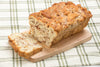 Loaf of soft, buttery apple fritter bread with visible cinnamon swirls and chopped apples, sliced on a wooden board, handcrafted and made in the USA, ideal for kitchen and food collections.