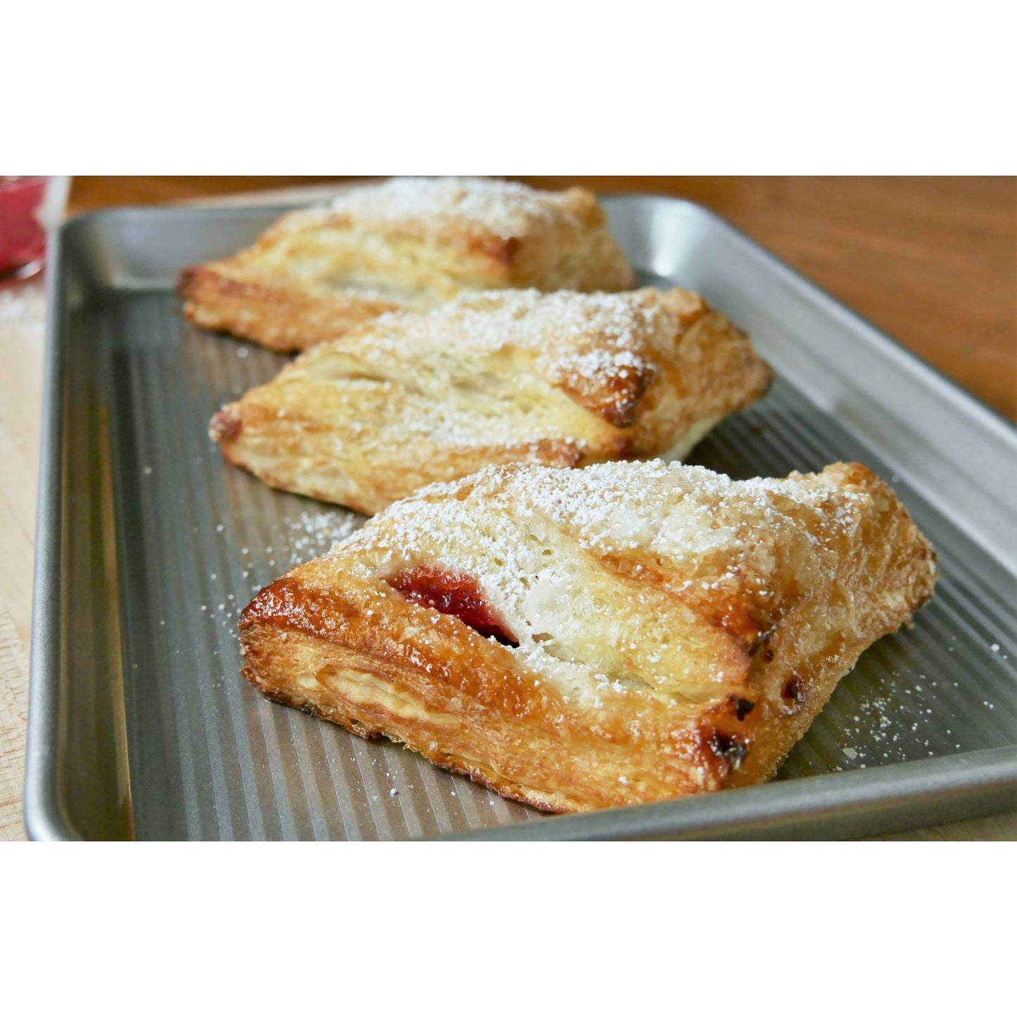 Ridged aluminized steel jelly roll pan holding freshly baked fruit-filled pastries dusted with powdered sugar, featured in Kitchen & Food, Baking Supplies, and USA Made collections.