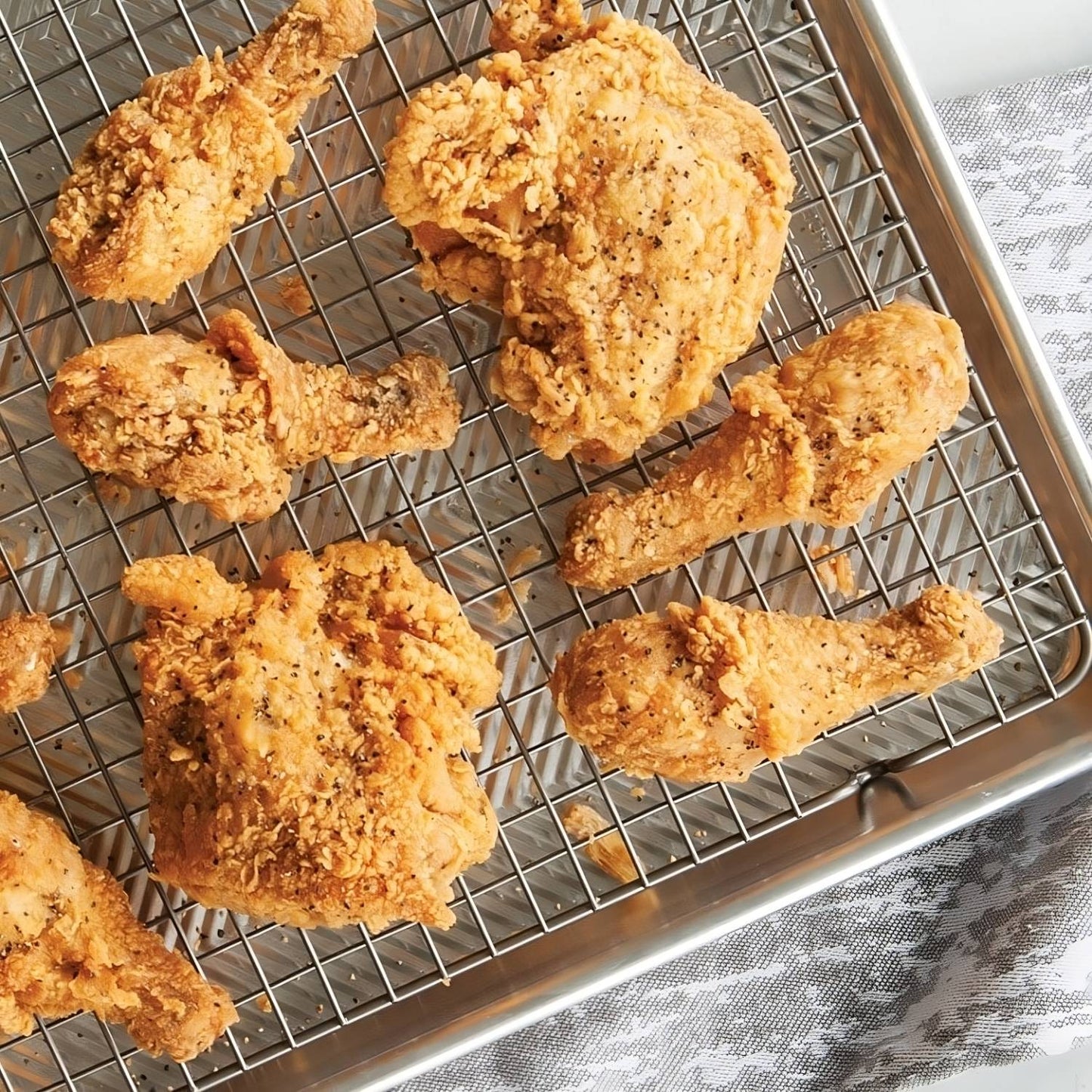 Golden crispy fried chicken pieces resting on a durable oven-safe grid atop a natural aluminum half-sheet pan, showcasing premium cookware ideal for Kitchen & Food and Baking Supplies collections.