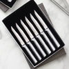 Set of six handcrafted steak knives with smooth stainless steel handles and single-sided serrated blades, made in the USA, ideal for kitchen, food prep, and knife collections.