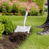 Person using a heavy-duty digging spade to turn soil in a garden bed next to green shrubs and manicured lawn, ideal for Farm, Garden & Tool, Digging and Cultivating, Lawncare, and Best Sellers collections.