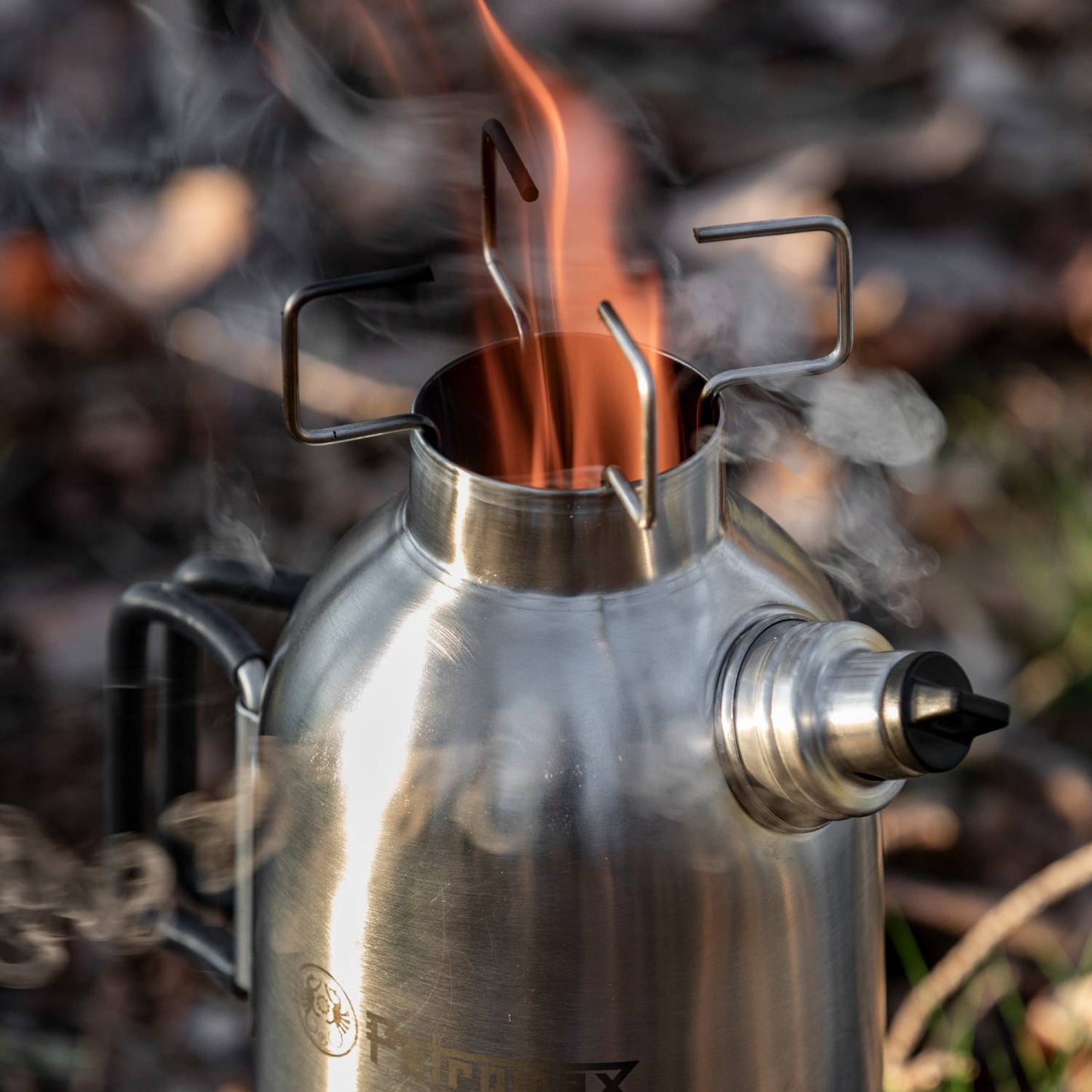 Close-up of a stainless steel fire kettle with flames and smoke rising from its top, featuring a sturdy handle and foldable pot supports; ideal for camping, emergency supplies, farm, garden & tool, and best sellers collections.