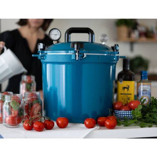 Blue 21.5-quart pressure canner with secure locking lid, pressure gauge, and sturdy handle surrounded by fresh tomatoes and jars for safe food preservation in Kitchen & Food, Food Preservation, and USA Made collections.
