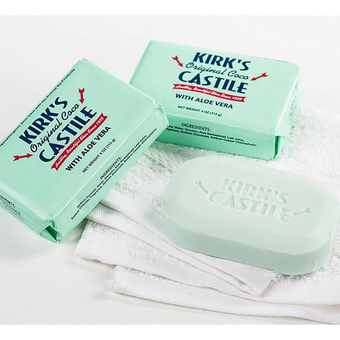 Three bars of pale green Kirk's Aloe Vera Castile soap with packaging and one unwrapped bar resting on folded white towels, ideal for Health & Wellness and Grooming collections, made in USA.