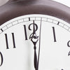 Close-up of a handcrafted clock face with black hour and minute hands pointing to twelve, featuring large black numerals on a white background, part of a heavy cast iron frame in a USA Made decor collection.