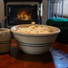 Handcrafted stoneware bowl with blue stripes filled with popcorn, set on a wooden table near a cozy fireplace, featured in Kitchen & Food and USA Made collections.