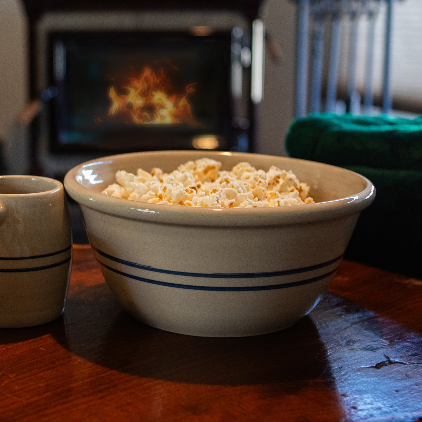 Handcrafted stoneware bowl with blue stripes filled with popcorn, set on a wooden table near a cozy fireplace, featured in Kitchen & Food and USA Made collections.