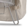 Close-up of a light beige ripstop fabric cover securing the metal leg of a fire bowl with a hook, designed for weather-resistant storage in camping, farm, and outdoor use.