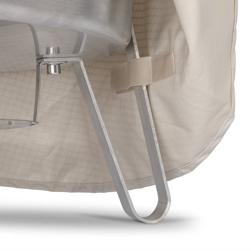 Close-up of a light beige ripstop fabric cover securing the metal leg of a fire bowl with a hook, designed for weather-resistant storage in camping, farm, and outdoor use.