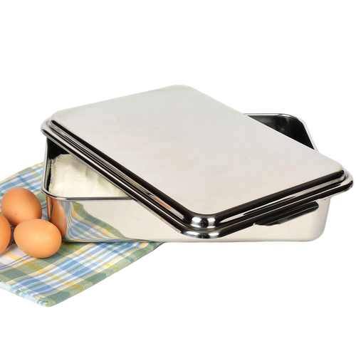 Open rectangular stainless steel cake pan with lid resting on a plaid cloth next to three brown eggs, ideal for baking and holiday hosting in the kitchen.