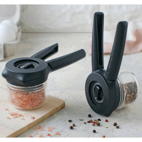 Two black-handled spice mills with clear containers filled with pink salt crystals and mixed peppercorns, designed for Kitchen & Food, Dinnerware, Kitchen Gadgets, Cooking and Baking Helpers, Storage and Serving, Best Sellers, and Promo Eligible collections.