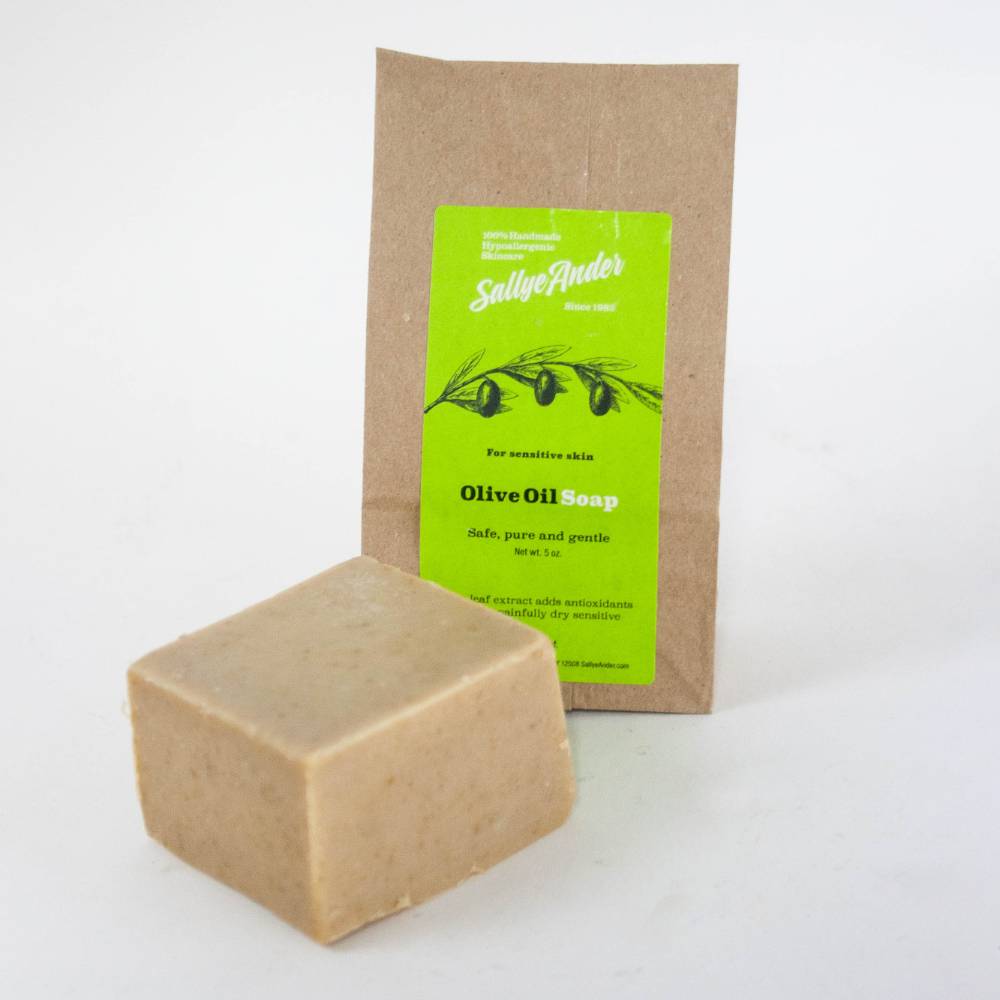 Handcrafted hypoallergenic olive oil soap bar with a smooth natural beige tone, accompanying kraft paper packaging with bright green label, made in USA for Health & Wellness and Soaps collections.