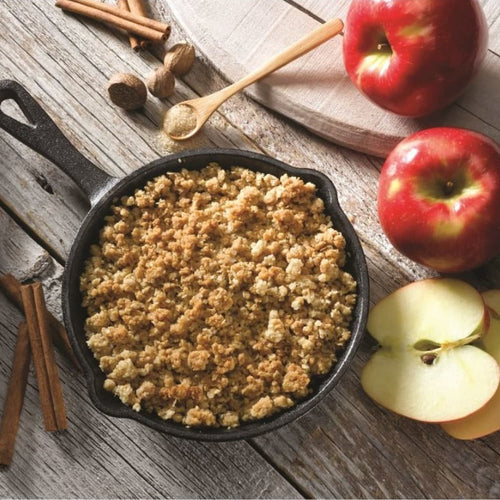Handcrafted apple crumble dessert baked in a black 6-inch cast iron skillet, styled with fresh red apples, cinnamon sticks, and spice on rustic wood, ideal for Kitchen & Food, Dry Goods and Mixes, Best Sellers, Promo Eligible collections.