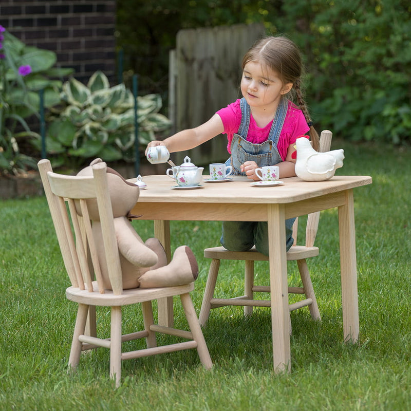 Child playing at a handcrafted, Amish-made wooden table and chair set with a tea party setup including a teddy bear and ceramic tea set, part of Toys, Books & Games and USA Made collections.