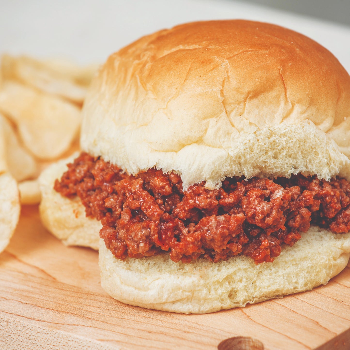 Close-up of a handcrafted sloppy joe sandwich with seasoned cooked ground beef on a soft bun, served with potato chips, perfect for Kitchen & Food, Meats, Best Sellers, and Promo Eligible collections.