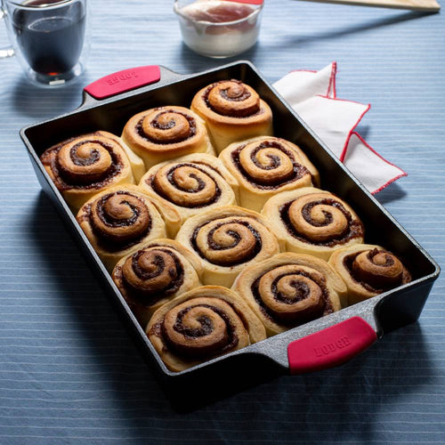 Handcrafted cast iron casserole pan with dual red silicone grips, filled with freshly baked cinnamon rolls, ideal for Kitchen & Food, Cookware, Cast Iron, USA Made, Best Sellers, and Promo Eligible collections.