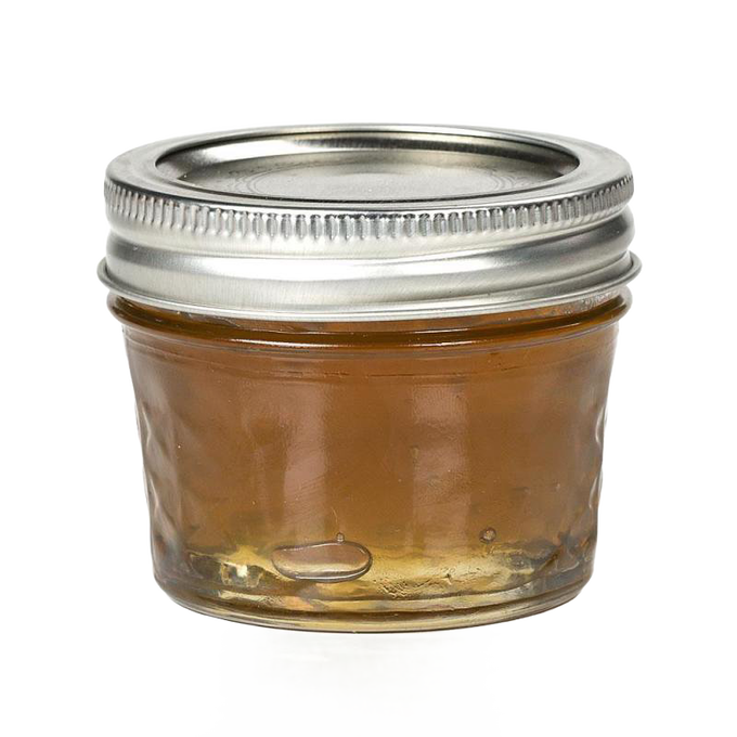 Small clear glass jar with quilted texture and silver metal lid, filled with golden jam, ideal for kitchen, food preservation, and canning uses, handcrafted in USA.