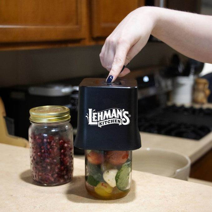 Black cordless vacuum sealer in use sealing a mason jar filled with pickled vegetables on a kitchen counter, featuring a one-touch button, featured in Kitchen & Food, Kitchen Gadgets, and Storage collections.