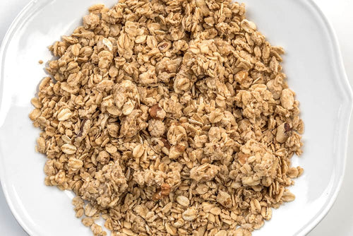 Close-up of handcrafted wholesome granola clusters and whole grain oats on a white plate, showcasing a natural, preservative-free snack from USA-made Amish products in Kitchen & Food collections.