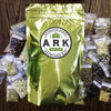 Shiny gold foil pouch labeled for heirloom seed kit surrounded by multiple small clear bags of assorted organic seeds, ideal for Farm, Garden & Tool and Seeds and Planting collections made in USA.