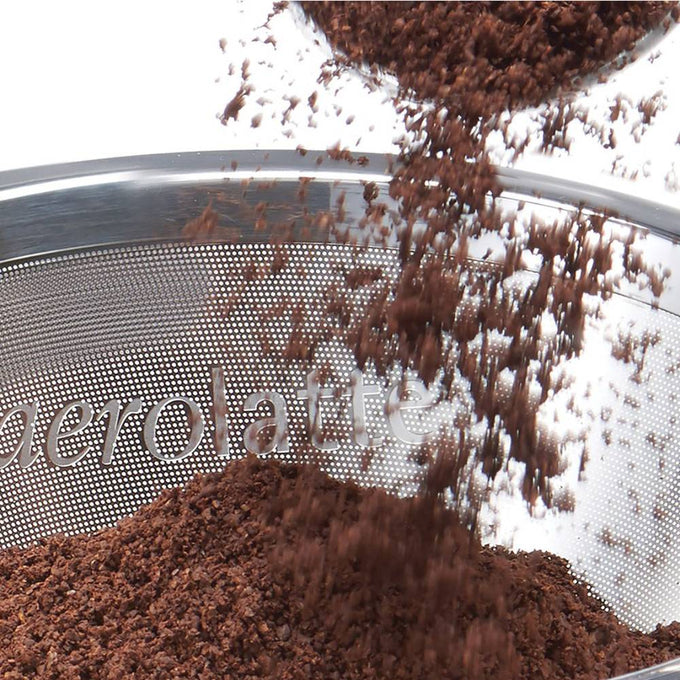 Close-up of fine coffee grounds falling into a stainless steel micro filter with the Aerolatte logo, designed for manual pour-over brewing in Kitchen & Food and Brewing Coffee collections.