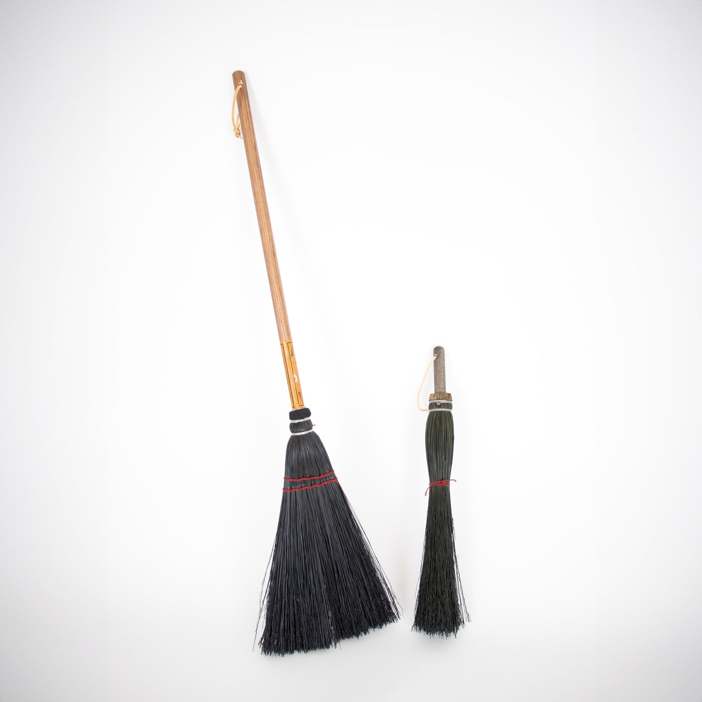 Pair of handcrafted Amish brooms with natural bristles and wooden handles, featuring hanging loops, ideal for cleaning hearths, stoves, and fireplaces, made in USA collections.
