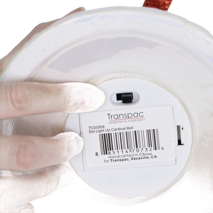 Close-up of a handcrafted dolomite bell’s underside showing a battery-operated switch and product label, highlighting its unique design for Home & Decor, Holiday Decor, and Promo Eligible collections.
