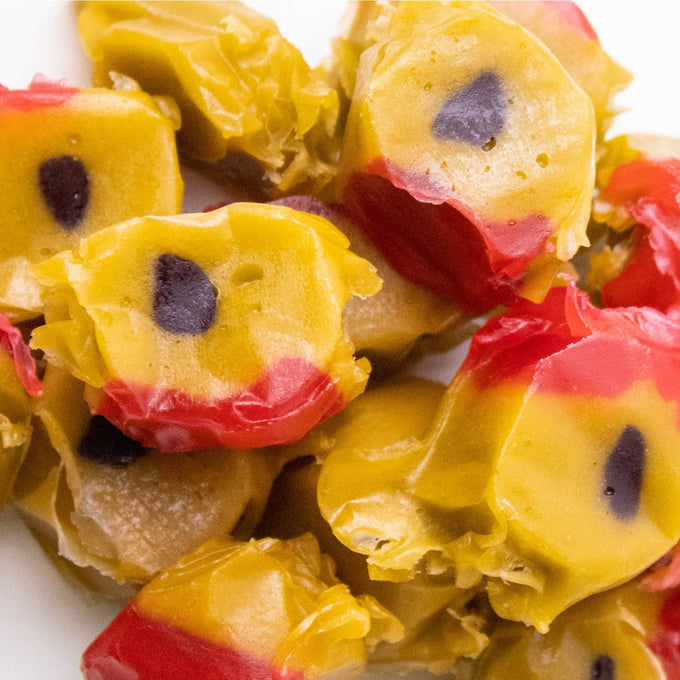 Close-up of handmade old-fashioned wrapped taffy candies with yellow, red, and black colors, evoking classic sweet memories from Kitchen & Food, Snacks and Sweets, Best Sellers, and Promo Eligible collections.