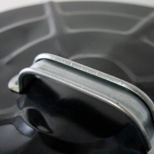 Close-up of a strong metal bail handle attached to a black painted steel lid, designed for secure lifting on a handcrafted ash pail used with stoves and hearth accessories in best sellers and promo collections.