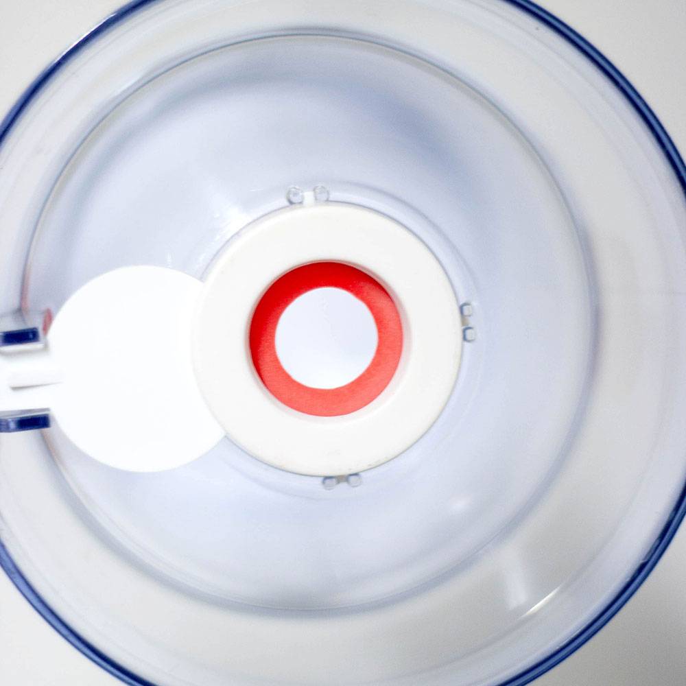 Top-down view of a clear plastic batter dispenser with a white and red valve at the center, designed for precise and mess-free pouring, featured in Kitchen & Food and Cooking and Baking Helpers collections.