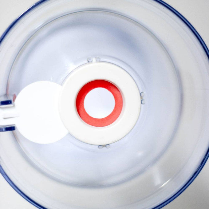 Top-down view of a clear plastic batter dispenser with a white and red valve at the center, designed for precise and mess-free pouring, featured in Kitchen & Food and Cooking and Baking Helpers collections.