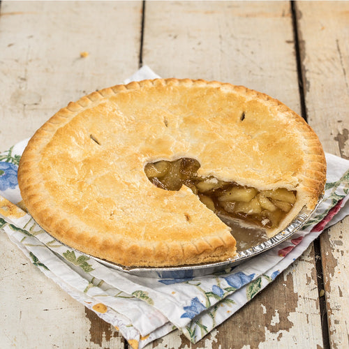 Golden brown homemade apple pie with a flaky crust and sweet, spiced apple filling, resting on a floral cloth on rustic wooden surface, perfect for farm and kitchen collections.