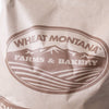 Close-up of a brown paper bag labeled with a rustic Montana Farms & Bakery logo featuring stylized mountains and farmland, suited for Farm, Garden & Tool, Kitchen & Food, and Pantry collections.