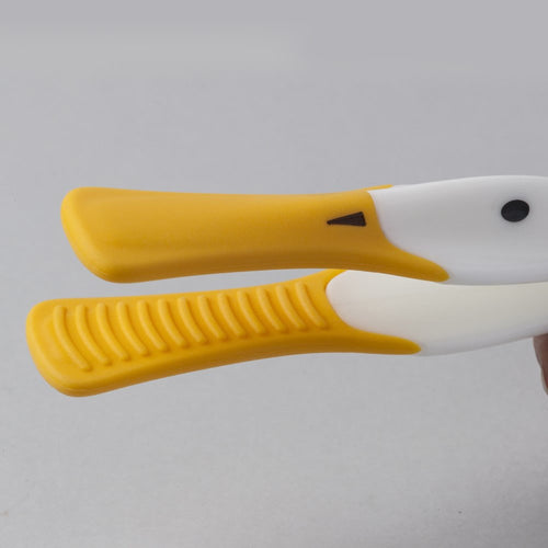 Close-up of yellow and white duck-shaped toast tongs with textured grip, featuring a heat-resistant silicone beak, designed for safe serving in kitchen gadgets and accessories collections.